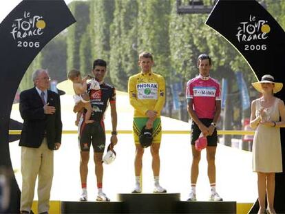 Óscar Pereiro, con su hijo Juan en brazos, Floyd Landis y Andreas Kloden, en el podio final del Tour ayer en París.