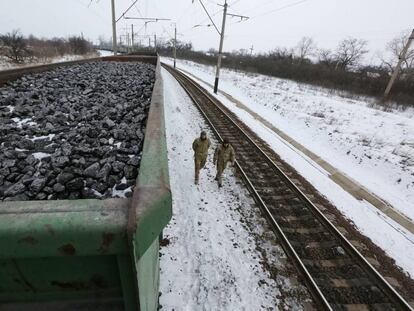 Activistas caminan frente a convoys cargados de carb&oacute;n bloqueados en una estaci&oacute;n en una aldea Ucrania