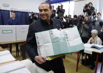 El exprimer ministro Silvio Berlusconi muestra su papeleta en un centro electoral de Milán.