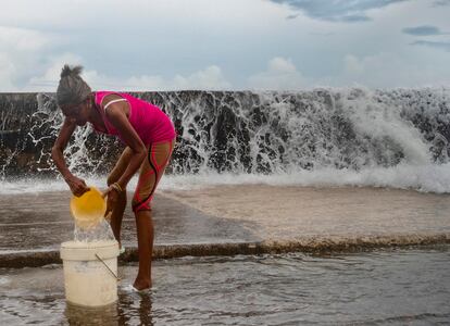 A woman collects seawater to clean her house, on the seafront in Havana (Cuba), in September 2022.