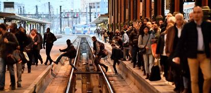 Passageiros cruzam as vias do trem em uma estação de Paris (França).