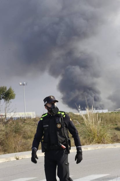 Un agente de policía local de Montornès del Vallès con mascarilla, en las proximidades del incendio. Los bomberos han solicitado que los trenes no efectúen parada en esta estación.