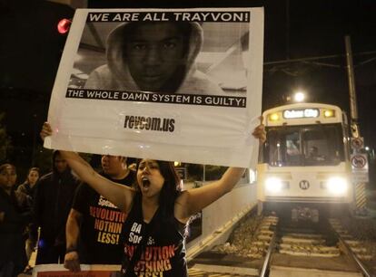 Varios manifestantes bloquean una línea de tren en Los Ángeles tras el fallo con un cartel que dice: “¡Todos somos Trayvon! ¡Todo el maldito sistema es culpable!”.
