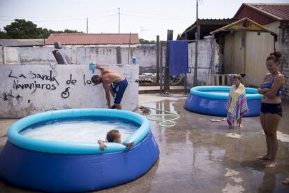 Varios vecinos se refrescan en una piscina hinchable, en una calle de El Vacie (Sevilla).