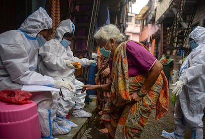 Personal sanitario toma la temperatura a una mujer mayor en Bombay (India).