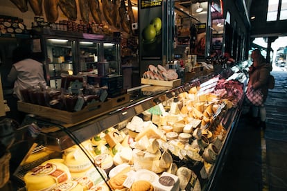 Varias personas compran en una tienda de quesos y embutidos en la plaza de abastos de Santiago de Compostela, este martes.