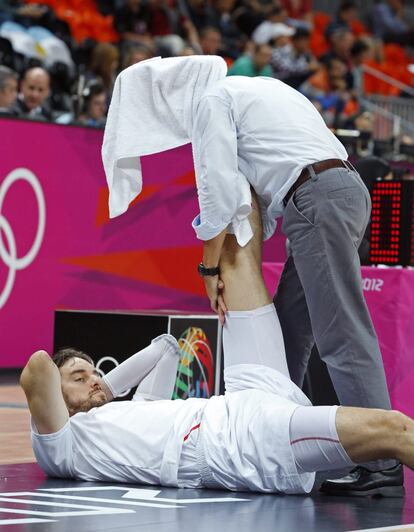 Claudio Coque, preparador físico de la selección española de baloncesto, hace estiramientos a Pau Gasol poco antes del inicio del partido.
