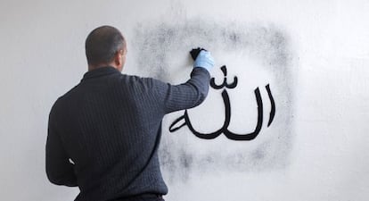 Un guardia civil toma huellas en una de las pintadas realizadas en el templo del Carmen de Rincón de la Victoria (Málaga).