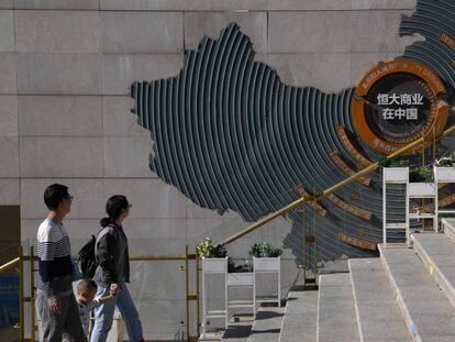 Viandantes pasan delante de un mapa que detalla las promociones inmobiliarias de Evergrande, en Pekin.