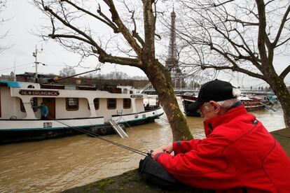 Un hombre utiliza una cuerda para entregar una bolsa con necesidades básicas a un amigo que vive en una casa barco y se ha quedado atrapado dentro por la crecida del Sena en París, el 25 de enero de 2018.  