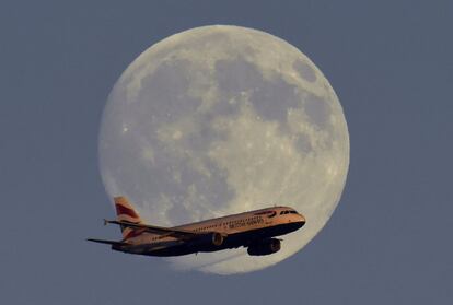 Un avión de pasajeros de British Airways pasa por delante de la luna en su trayecto hacia el aeropuerto de Heathrow, en Londres.