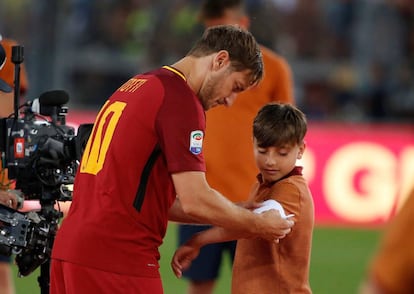 Totti cede su faja de capitán a un niño de los juveniles de la Roma tras su discurso de despedida.