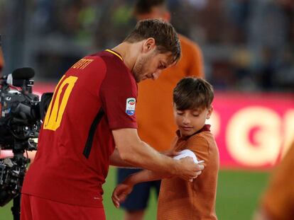 Totti cede su faja de capitán a un niño de los juveniles de la Roma tras su discurso de despedida.