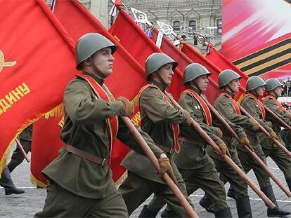 Soldados rusos con uniformes de la II Guerra Mundial marchan con banderas comunistas por la plaza Roja de Moscú.