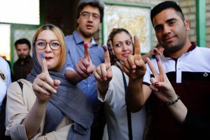 Votantes muestran sus dedos manchados en tinta tras depositar su voto en un centro electoral en Teherán.