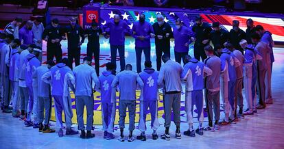 Los jugadores de los Lakers y los Spurs escuchan juntos el himno antes de su partido.