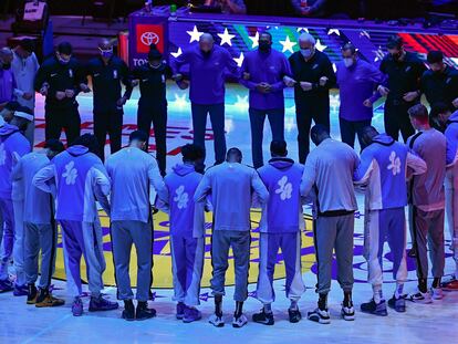 Los jugadores de los Lakers y los Spurs escuchan juntos el himno antes de su partido.