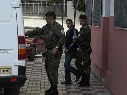 Dos policías militares trasladan a uno de los detenidos en Ceuta.