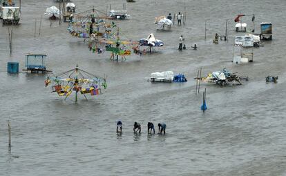 Gente caminando por un área inundada de Marina Beach, en la bahía de Bengal, después de las fuertes tormentas que han azotado Chennai (India).
