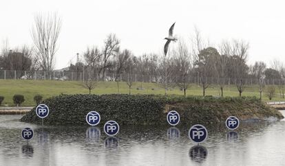 Una gaviota vuela cerca de los logotipos del Partido Popular, frente a la Caja Mágica de Madrid.