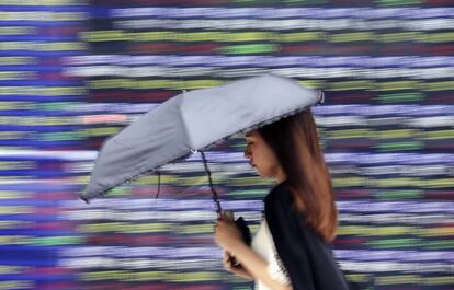 Una mujer camina por delante de una pizarra electrnica en Tokio, Japn.