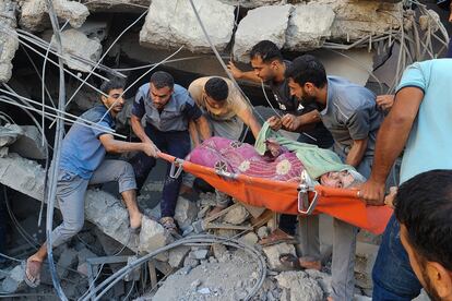 Un grupo de voluntarios rescatan a una mujer entre los escombros de un edificio atacado este sábado por el ejército israelí en Deir al Balah, en la franja de Gaza. 