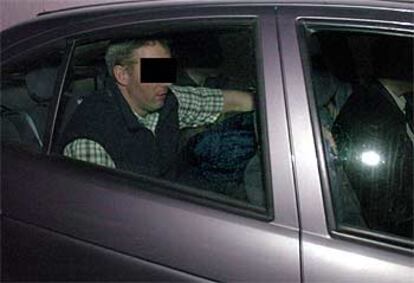 Un policía oculta con el brazo el rostro de uno de los dos presuntos miembros de ETA detenidos en Bélgica.