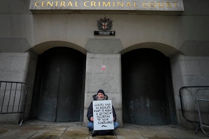 A demonstrator holds a banner outside The Old Bailey, the Central Criminal Court of England and Wales, in London, Monday, Dec. 4, 2023