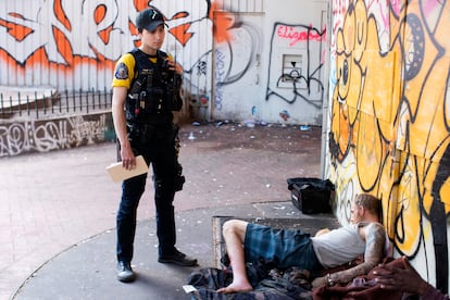 An officer stands next to a person who appears to be passed out on May 18, 2023, in downtown Portland, Oregon.