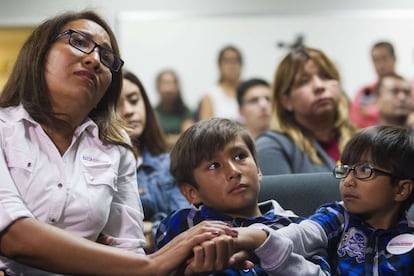 Una mujer escucha el mensaje del presidente Obama sobre las medidas migratorias mientras toma la mano de sus dos hijos en Los Ángeles, California