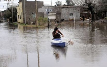 Un hombre rema por una calle inundada en Arrecifes, provincia de Buenos Aires