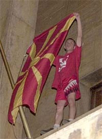 Un joven macedonio levanta la bandera nacional dentro del Parlamento de Skopje después de que un grupo lograra forzar las puertas del edificio y entrar.