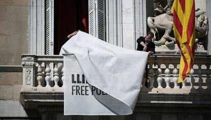 Treballadors del palau de la Generalitat retiren les pancartes a favor dels presos del balcó de l'edifici.
