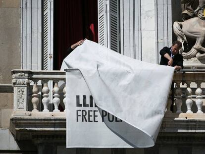 Treballadors del palau de la Generalitat retiren les pancartes a favor dels presos del balcó de l'edifici.