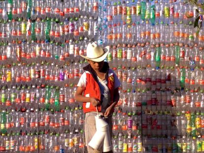 Uno de los obreros improvisados, frente a la pared de botellas de la futura casa de Lupita.