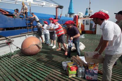 Trabajadores de Cruz Roja, Caritas y UGT suben alimentos al <i>Earsten Planet.</i>