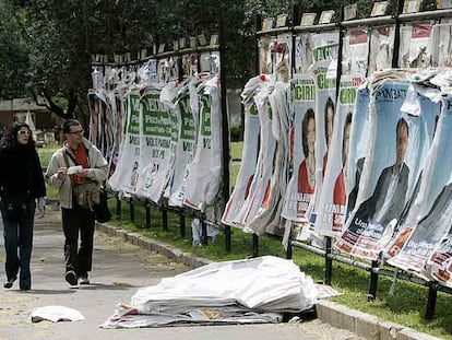 Dos viandantes miran los carteles electorales de diferentes partidos en una calle de Roma.