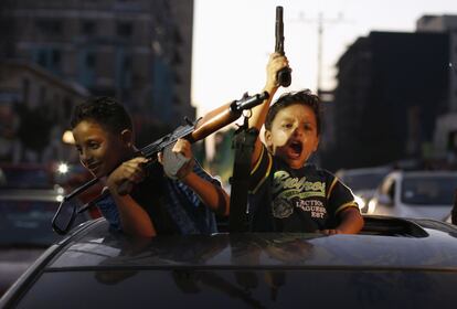 Dos niños palestinos juegan con pistolas mientras celebran dentro de un coche el cese de las hostilidades en la franja.
