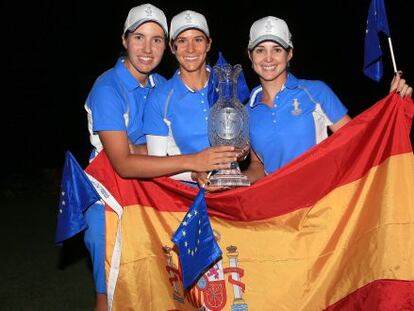 Carlota Ciganda (i), Azahara Muñoz (c) y Beatriz Recari posan con la Solheim Cup tras la bandera de España.