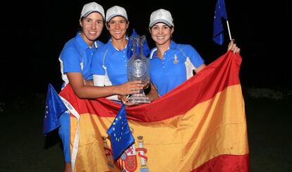 Carlota Ciganda (i), Azahara Muñoz (c) y Beatriz Recari posan con la Solheim Cup tras la bandera de España.