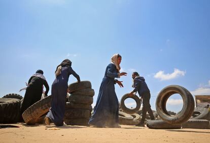 Mujeres y hombres palestinos amontonan neumáticos para hacer una barricada cerca de la frontera israelí. 