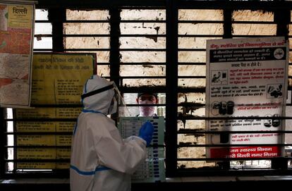 Un trabajador sanitario se prepara para tomar una muestra de un hombre en una escuela convertida en un centro para realizar pruebas de coronavirus, en Nueva Delhi (India).