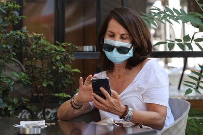 Una mujer con mascarilla revisa su teléfono en una terraza del centro de Madrid.