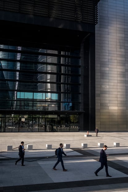 Varios hombres acuden a su puesto de trabajo en la zona de las Cuatro Torres de Madrid. Al fondo, la torre Cepsa.