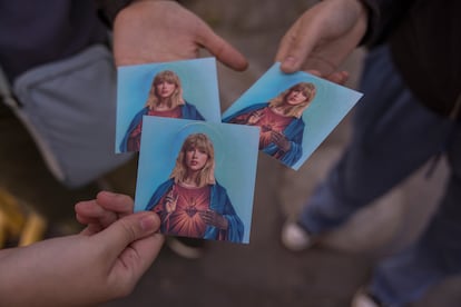 A woman holds cards showing Taylor Swift represented as Jesus Christ, the night before the concert she gave at the El Monumental stadium in Buenos Aires on November 8.