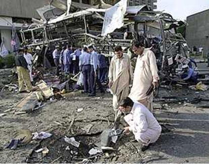 Agentes de seguridad paquistaníes inspeccionan los restos del autobús.