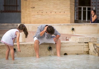 Un hombre y su hija se refrescan en una fuente de la Plaza del Pilar de Zaragoza, el pasado 21 de mayo.
