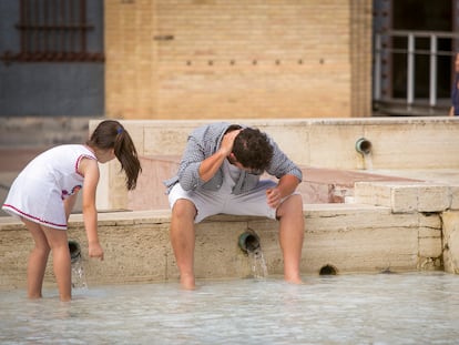 Un hombre y su hija se refrescan en una fuente de la Plaza del Pilar de Zaragoza, el pasado 21 de mayo.