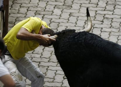 En la foto, uno de los toros empitona a un mozo en el tramo del Callejón.