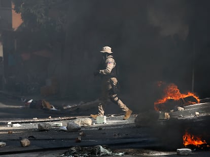 Un policía despeja una carretera bloqueada por manifestantes en el barrio Lalue de Port-au-Prince, Haití, el miércoles 14 de julio de 2021.